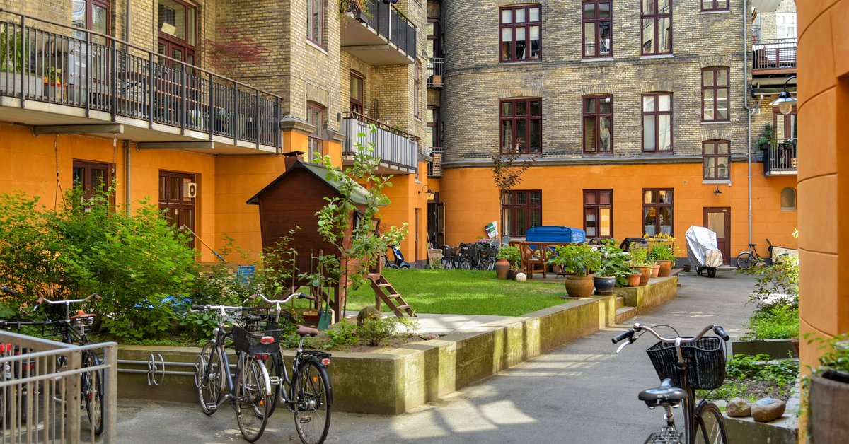 Baggård i København med cykler, græsplæne og altaner på etageejendommene