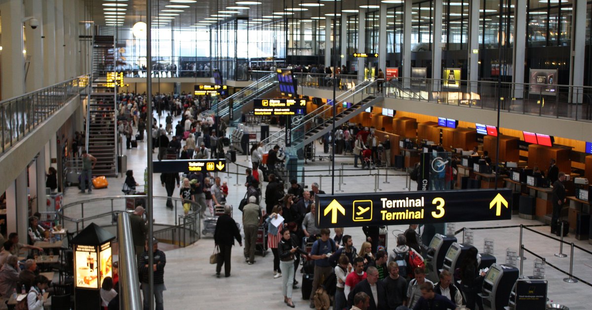 Rejsende med kufferter i afgangshallen i Københavns Lufthavn ved skiltet til Terminal 3